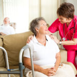 nurse leaning in to speak to elderly woman